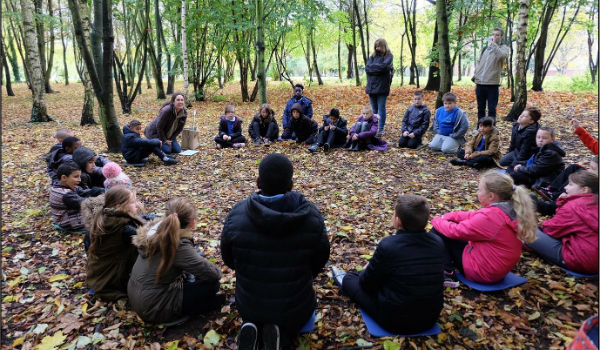 Kids sitting in a circle in the woodland at clifton park